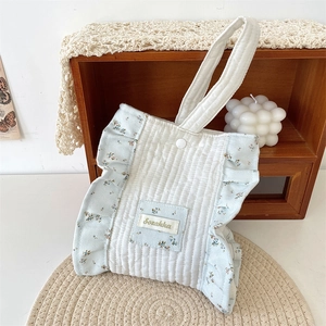 Detailed close-up of quilted floral handbag featuring blue ruffles and a snap closure