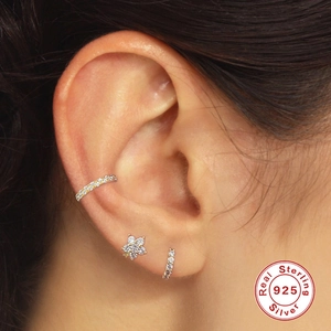 Macro shot of S925 sterling silver earring set with star and flower motifs on ear