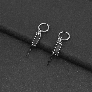 Detail of silver drop earrings featuring black rectangular pendants and fine dot chains