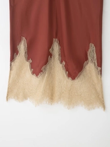 Detail view of reddish brown satin skirt with elegant champagne lace hem and mesh trim