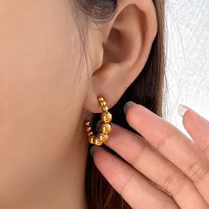 Polished 18K gold plated stainless steel beaded hoop earrings worn on model's ear