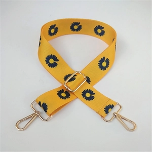 Detail of yellow daisy pattern fabric bag strap with golden metal swivel hooks