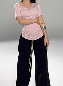 Detail of pink V-neck t-shirt and black wide-leg trousers with long beige drawstrings