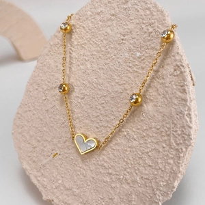 Detail of gold heart pendant with mother of pearl inlay and sparkling zircon beads