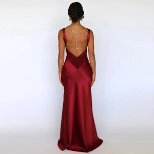 Close-up of a red satin backless evening dress featuring a decorative pearl chain detail