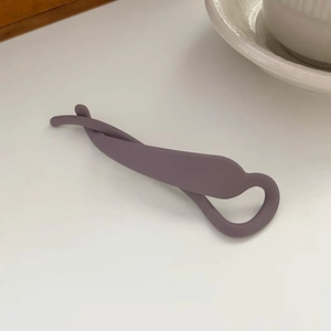 Détail d'une pince à cheveux banane violette mate avec un design torsadé sur fond blanc