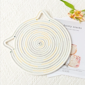 Detailed close-up of cat-eared woven placemat with colorful stitching on beige cotton