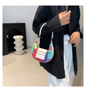 Detail of white crescent bag featuring colorful patchwork squares and metal buckle hardware