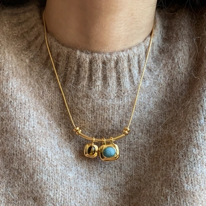 Collier plaqué or 18 carats avec pendentifs oeil de tigre porté sur un pull beige
