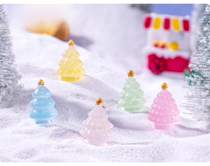 Miniature resin luminous Christmas trees in macaron colors on artificial snow background