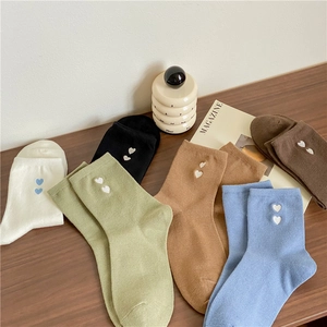 Detail of knit socks with heart embroidery in various colors on a wooden table