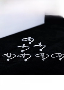 Detailed view of sterling silver letter rings with sparkling crystals on black surface