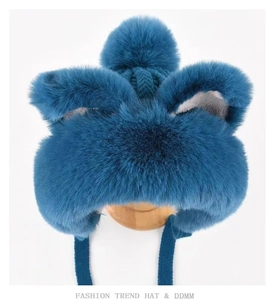 Detailed view of dark blue plush winter hat featuring soft fox ears and fluffy pom-pom detail