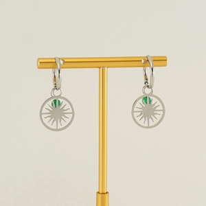 Détail de créoles argentées avec pendentif soleil et perle verte sur un support