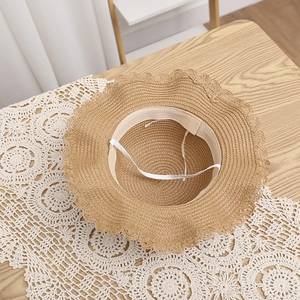 Close-up of woven straw sun hat interior with wavy brim and elastic chin strap