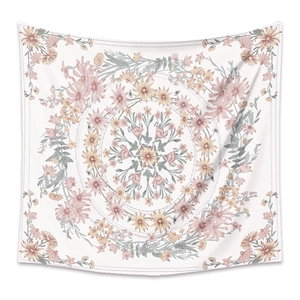 Close-up of bohemian mandala tapestry featuring pink and yellow floral patterns on white fabric