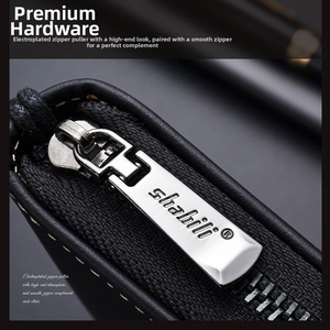 Macro detail of the premium silver-plated metal zipper and logo on a black leather wallet