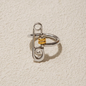 Minimalist silver paperclip ring with 18k gold beads on textured neutral stone surface