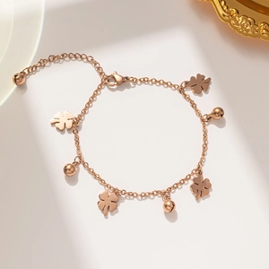 Elegant rose gold four-leaf clover bracelet with bell pendants on plain background