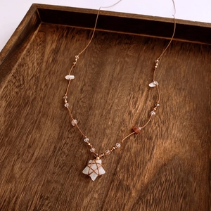 Detail of rose quartz star pendant necklace with gravel beads on brown woven cord
