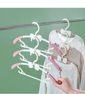 Detail showing the space-saving vertical stacking hook and bow tie design on white baby hangers