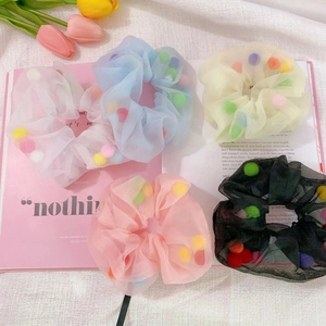 Detail of colorful pom poms inside translucent mesh scrunchies in pastel colors