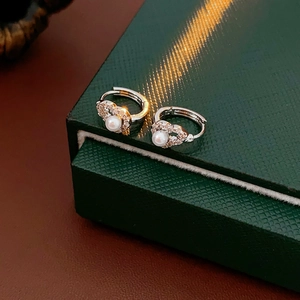 Close-up of heart-shaped silver earrings with sparkling zircon and pearls on a green box