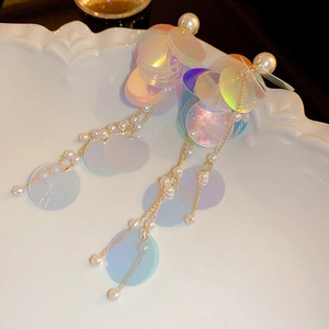 Detail of long tassel earrings with iridescent sequins and white pearls on gold chain