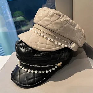 Quilted leather newsboy hats in beige and black with pearl chain and gold button details
