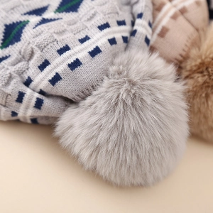 Detailed macro shot of grey fluffy pom-pom and geometric jacquard knit fabric on kids hat