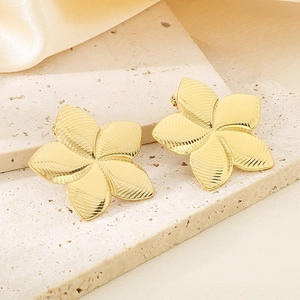 Macro detail of 18K gold stainless steel flower earrings with brushed texture