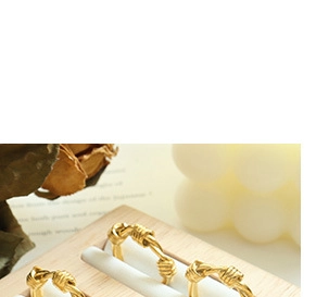 Close-up of golden knot rings on a display stand with warm decorative background