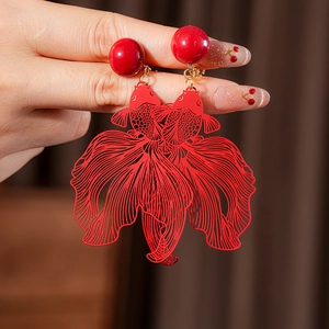 Vue détaillée de boucles d'oreilles carpe koï rouges ajourées sur l'oreille du mannequin