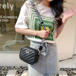 Quilted black crossbody camera bag with wide patterned strap and golden logo detail