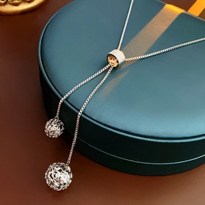 Détail d'un collier réglable en titane avec pendentifs boules évidées et zircons brillants