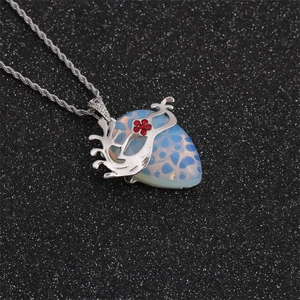 Détail du collier à chaîne torsadée argentée avec pierre rouge et pendentif à motifs