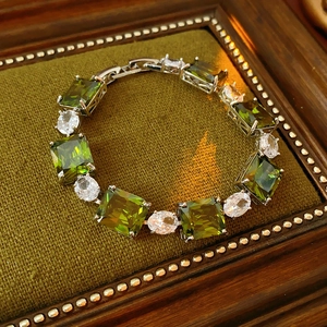 Detail of square olive green zircon and oval clear stones set in a silver bracelet