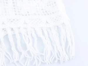 Dettaglio di pizzo all'uncinetto con frange lunghe sul top in maglia bianca