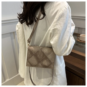 Detailed view of brown crossbody square bag with quilted pattern and leather strap