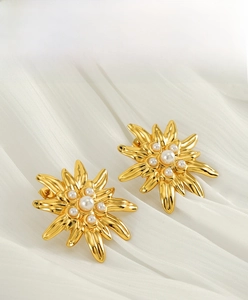 Detailed shot of gold daisy stainless steel earrings with elegant white pearls on silk
