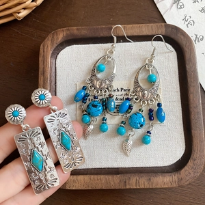 Detailed view of turquoise ethnic earrings with retro floral carving and leaf charms