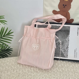 Detail of pink drawstring bag featuring a white lace heart and ribbon bow design