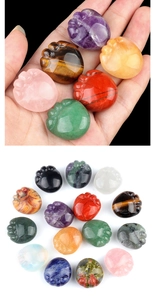 Hand holding various natural crystal cat paw stones showing small sizes and textures