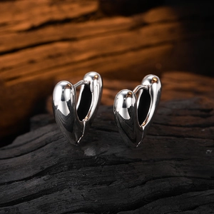 Macro close-up of heart-shaped silver hoop earrings with a high-polish mirror finish