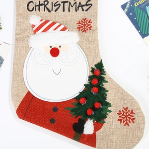 Close-up of burlap Christmas stocking featuring Santa Claus and tree embroidery detail