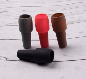 Detail view of silicone wine stoppers in gray red brown and black on wood background