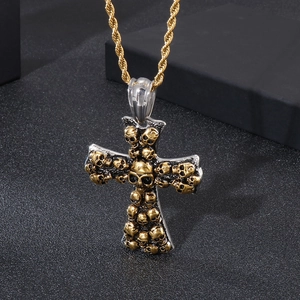 Detailed close-up of a silver cross pendant with a skull on a gold twisted rope chain