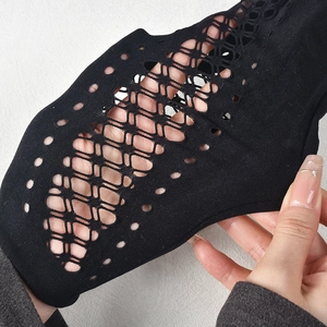 Détail du tissu en maille noire extensible montrant le motif évidé et la texture fine