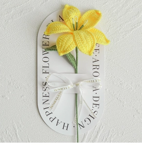 Detailed view of a hand-knitted yellow lily flower tied with a happiness ribbon