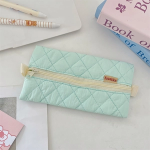 Detailed macro view of mint green quilted fabric pencil case with diamond pattern texture